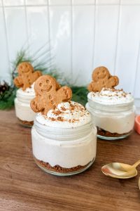 3 gingerbread cottage cheesecake jars with gingerbread man cookie on top