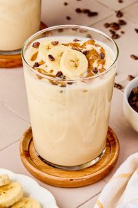 peanut butter smoothie in a glass cup on a coaster