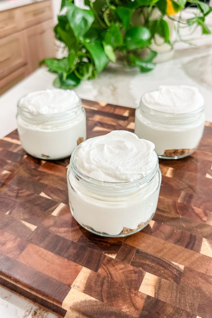 cheesecake layer added to the top of the crust layer in the jars