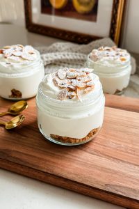 3 almond croissant cheesecake jars on a wooden cutting board