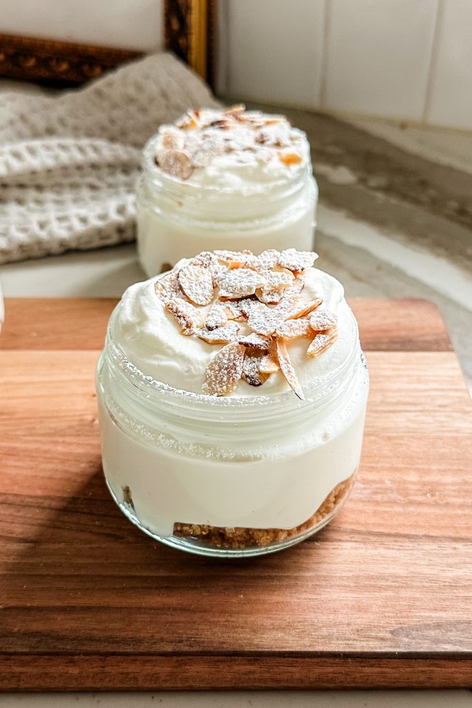 cheesecake jars topped with almonds and powdered sugar