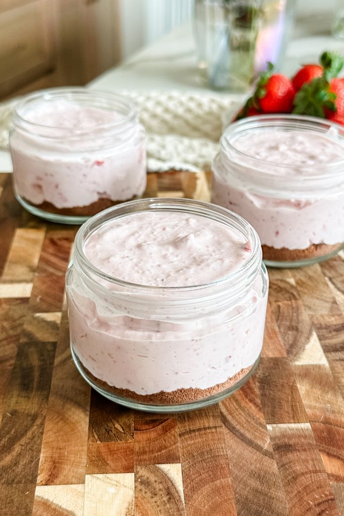 strawberry cottage cheese mix layered in top of cookie crumbs in a jar