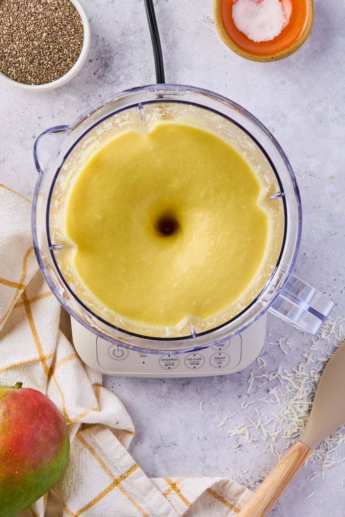 milk, mango, shredded coconut, maple syrup, vanilla, and a pinch of salt blending in a blender