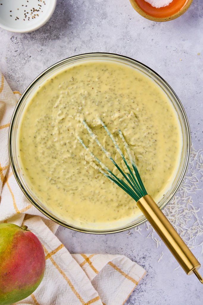 chia seeds being whisked into pudding mixture in a glass bowl