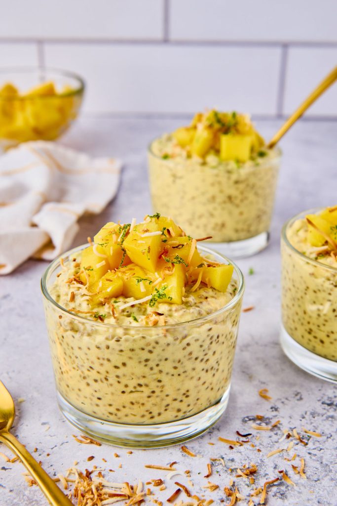 mango chia pudding in glass bowls topped with mango coconut and lime zest on top