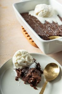 brownie pudding scooped on a plate with a scoop of ice cream