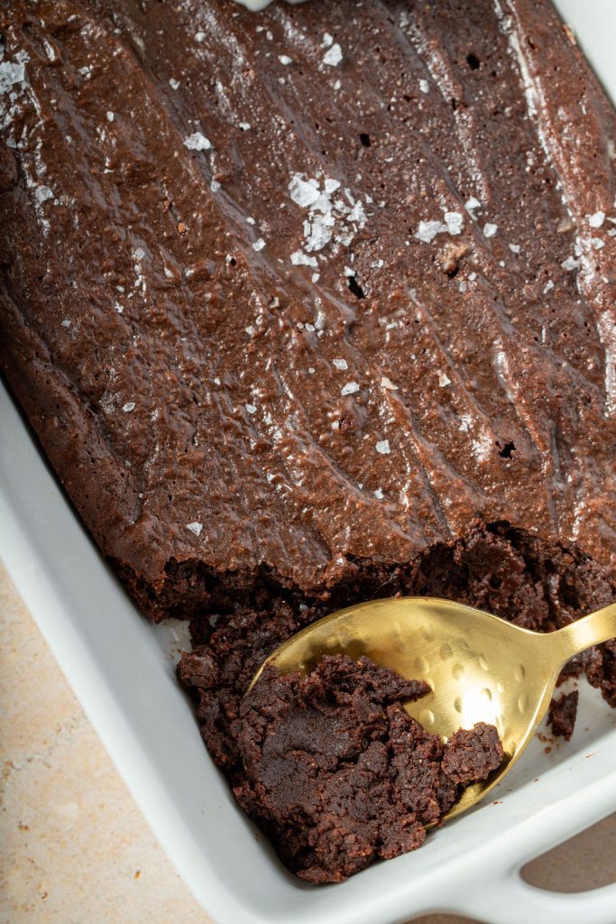 close up of bake brownie pudding with a gold spoon