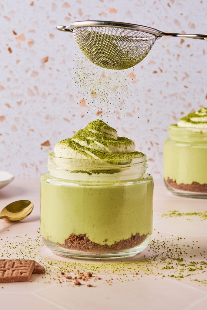 matcha cheesecake jar being dusted with matcha powder