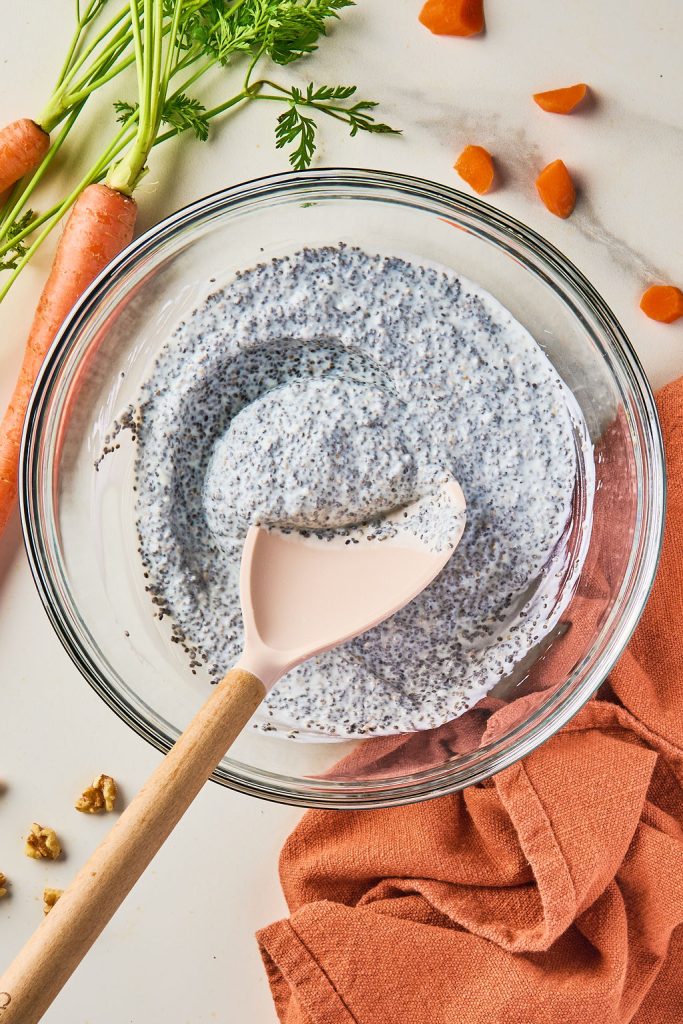 chia seeds and Greek yogurt mixed in a glass bowl with a silicone spoon