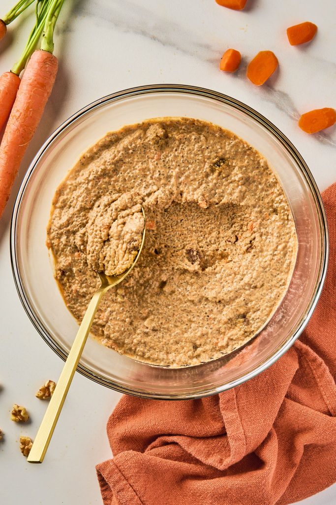thickened chia pudding being scooped in a glass bowl with a gold spoon