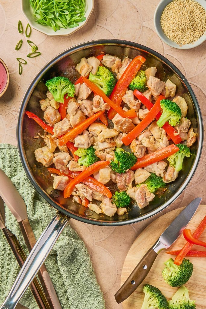 bell pepper and broccoli added to cooked chicken in skillet