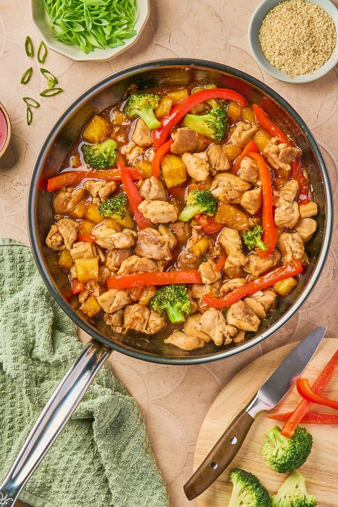sauce poured over chicken and veggies in skillet