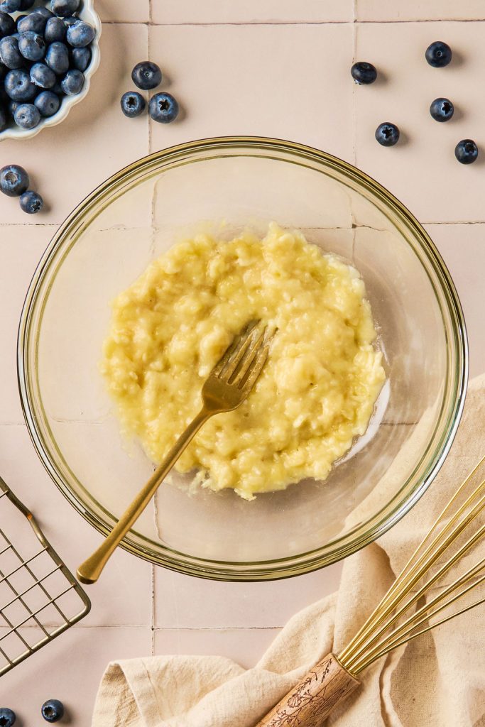 bananas mashed into a glass bowl with a fork