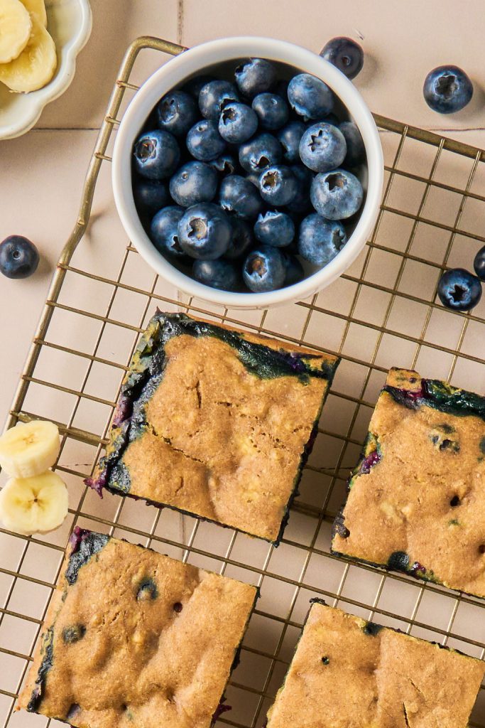 blueberry banana oatmeal bars on a wire rack with a bowl of blueberries