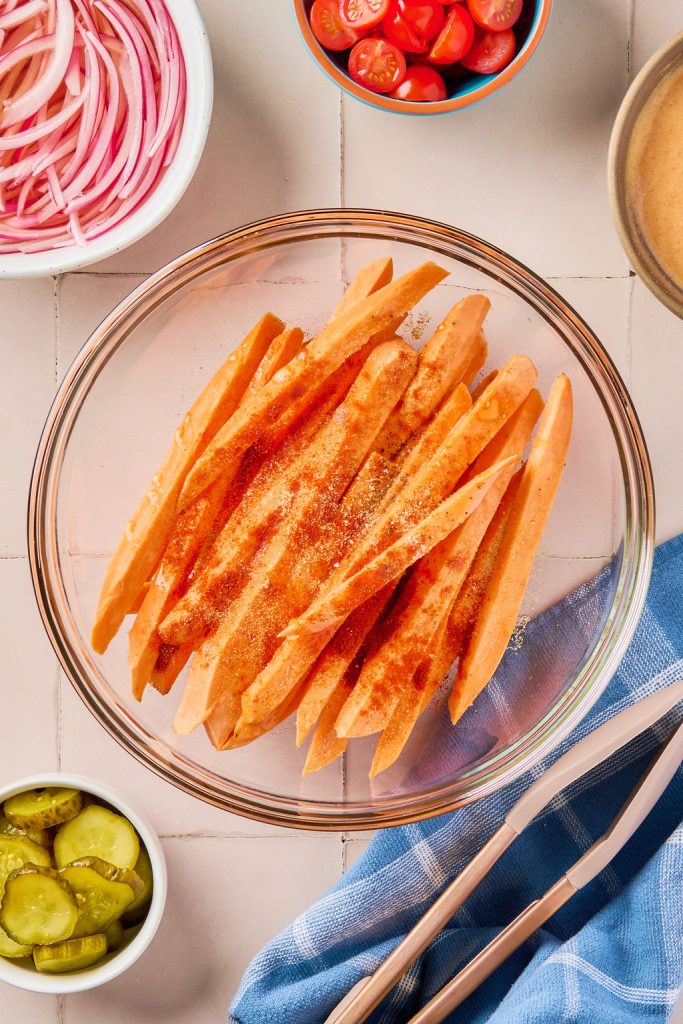 sweet potatoes cut into fries and seasonings added in a bowl