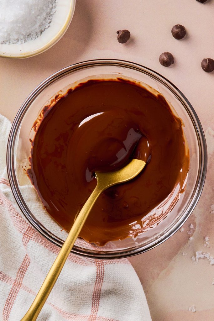 melted chocolate in a glass bowl with a gold spoon