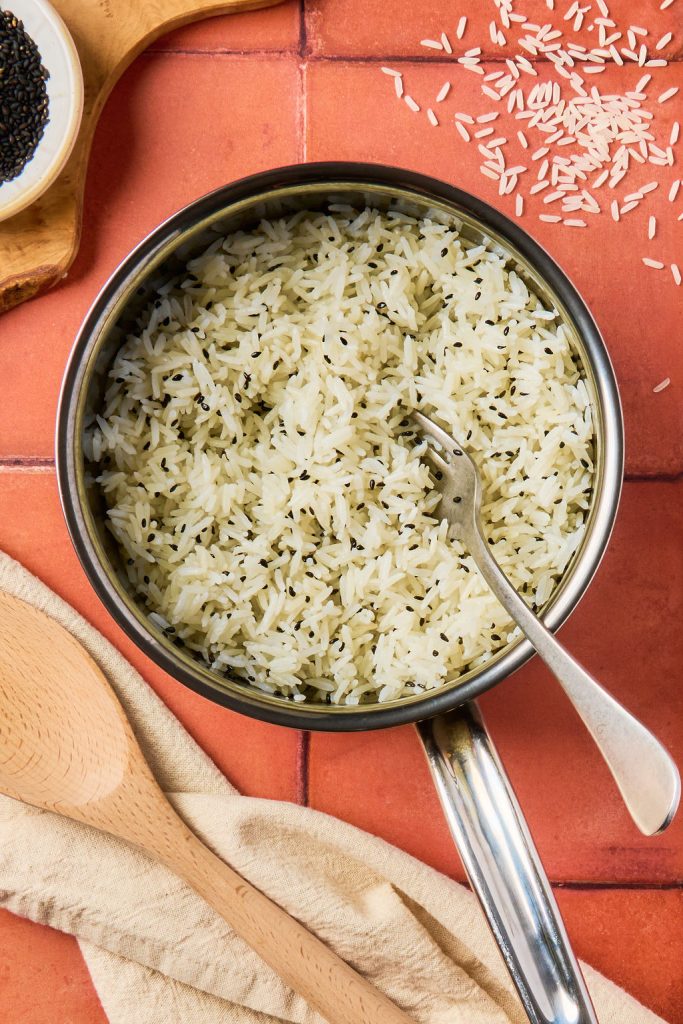 sesame seeds mixed into jasmine rice with a fork