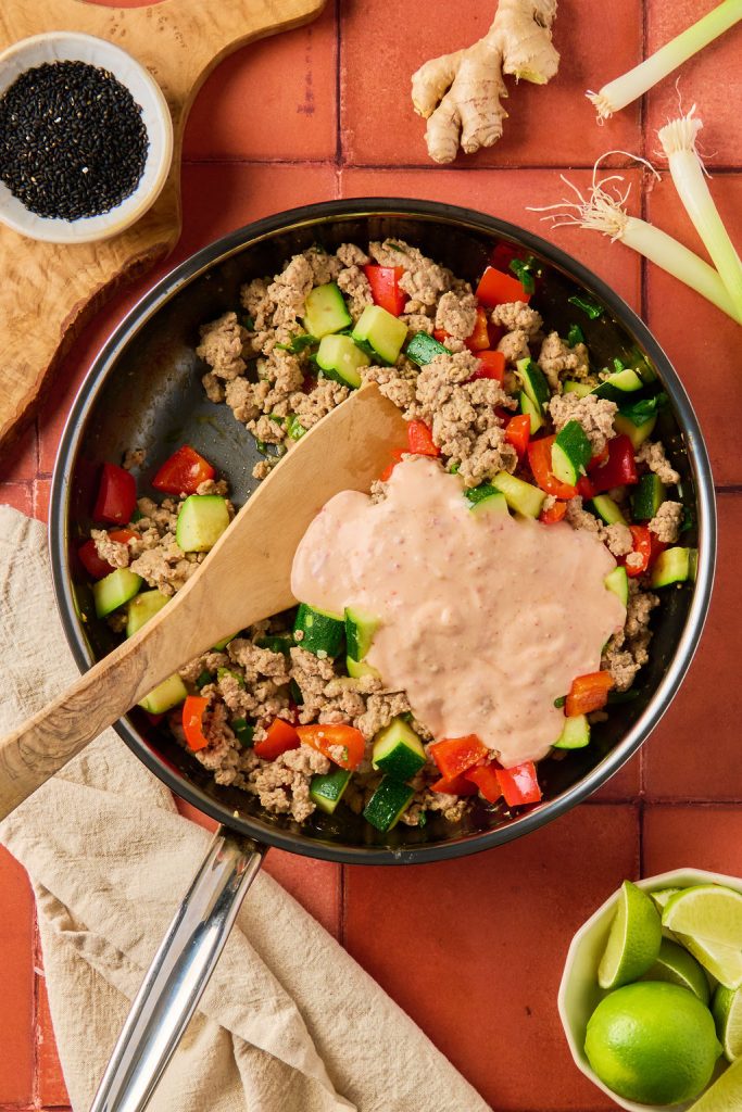 bang bang sauce added to the meat and veggies in a skillet