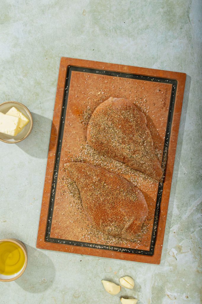 chicken breasts seasoned on a cutting board