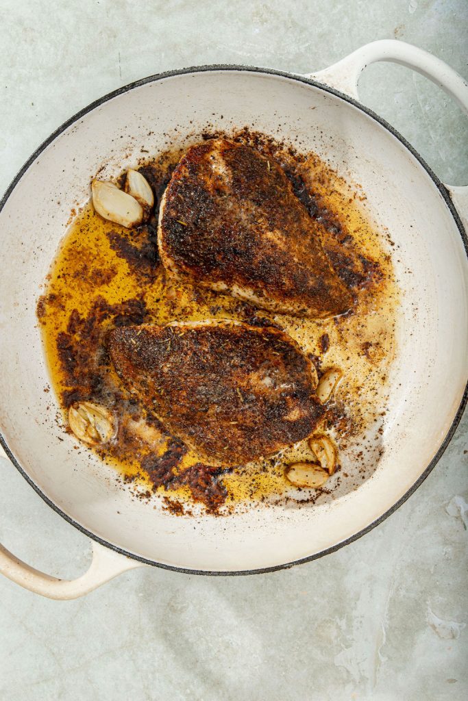 butter and garlic added to the chicken in the skillet