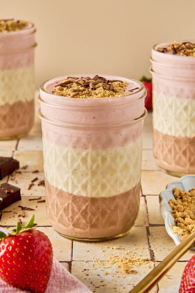 neapolitan cheesecake jar topped with graham crackers and shaved chocolate