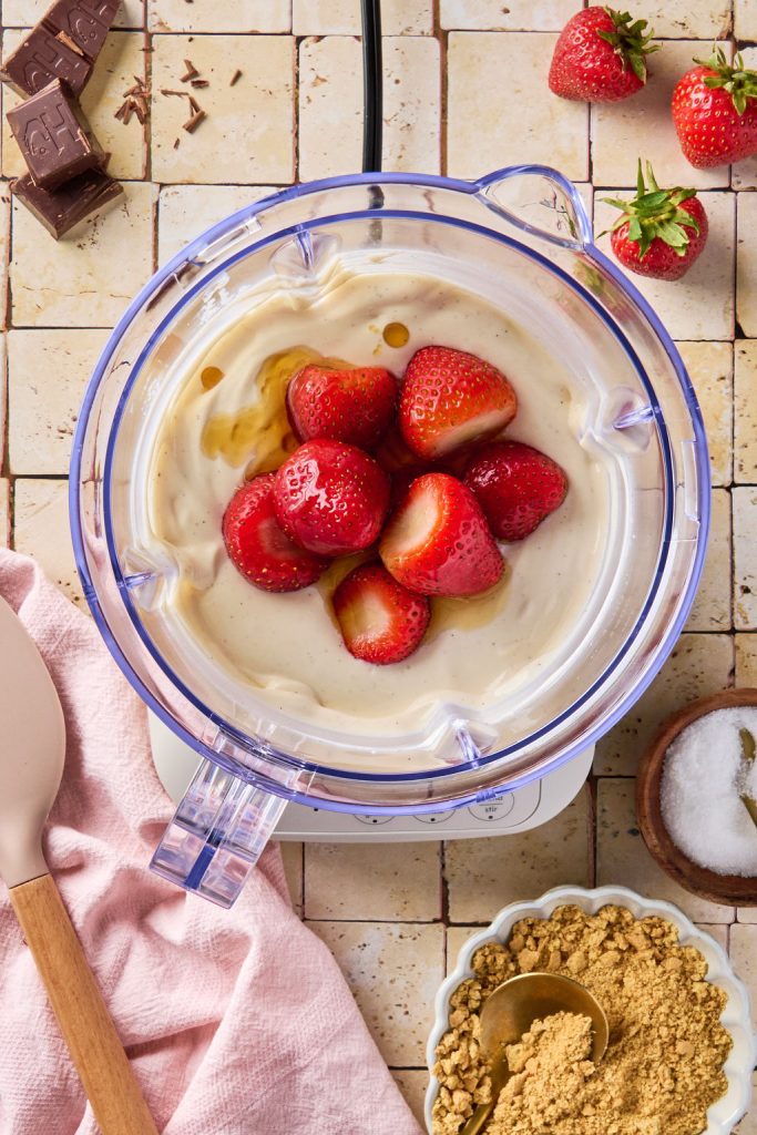 strawberries added to cheesecake base in a blender