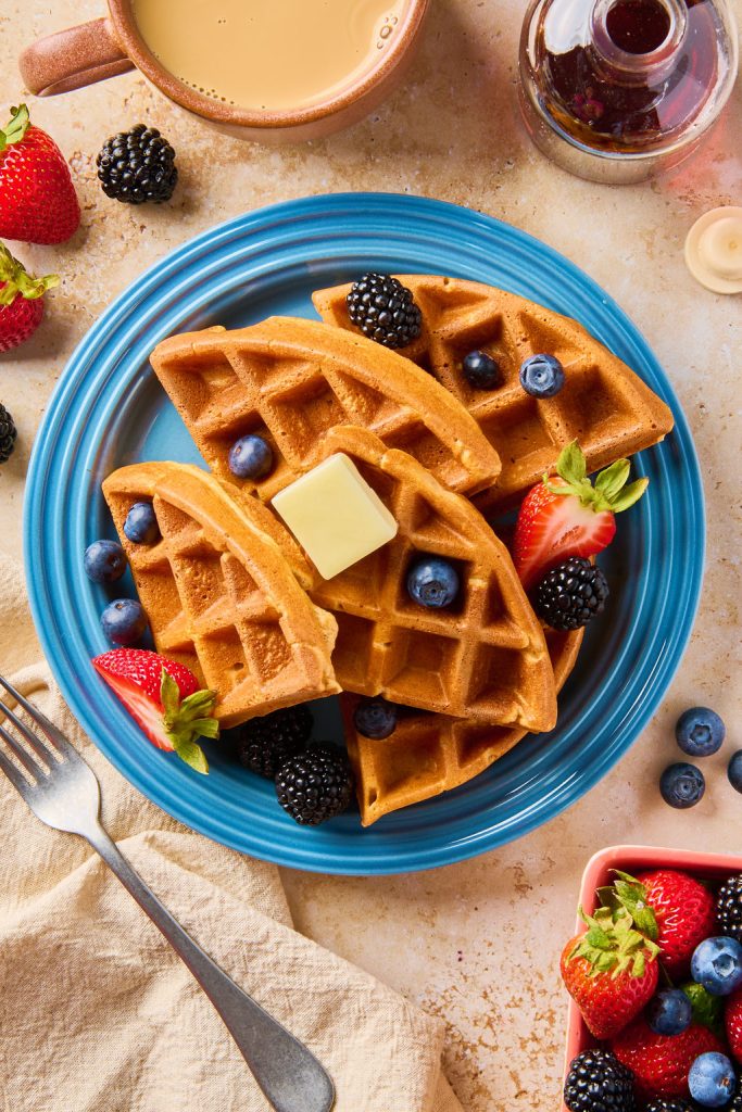 cottage cheese waffles on a blue plate topped with berries and butter