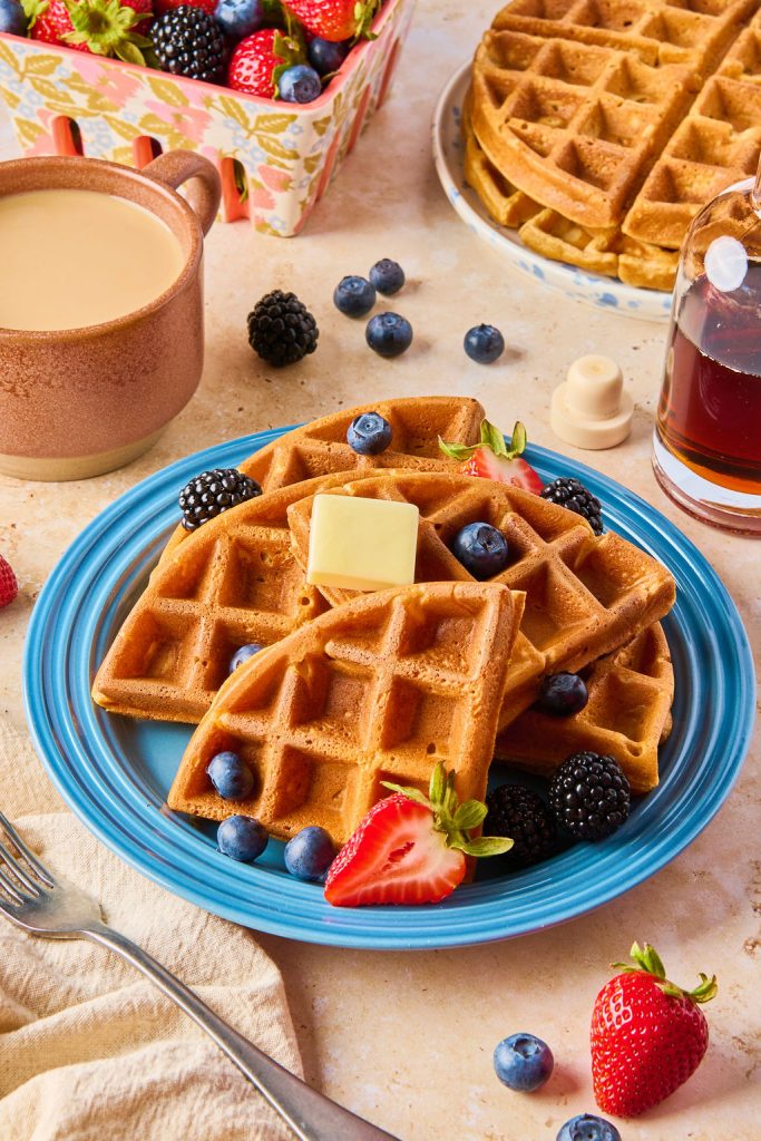 cottage cheese waffles on a plate with butter, berries and a cup of coffee