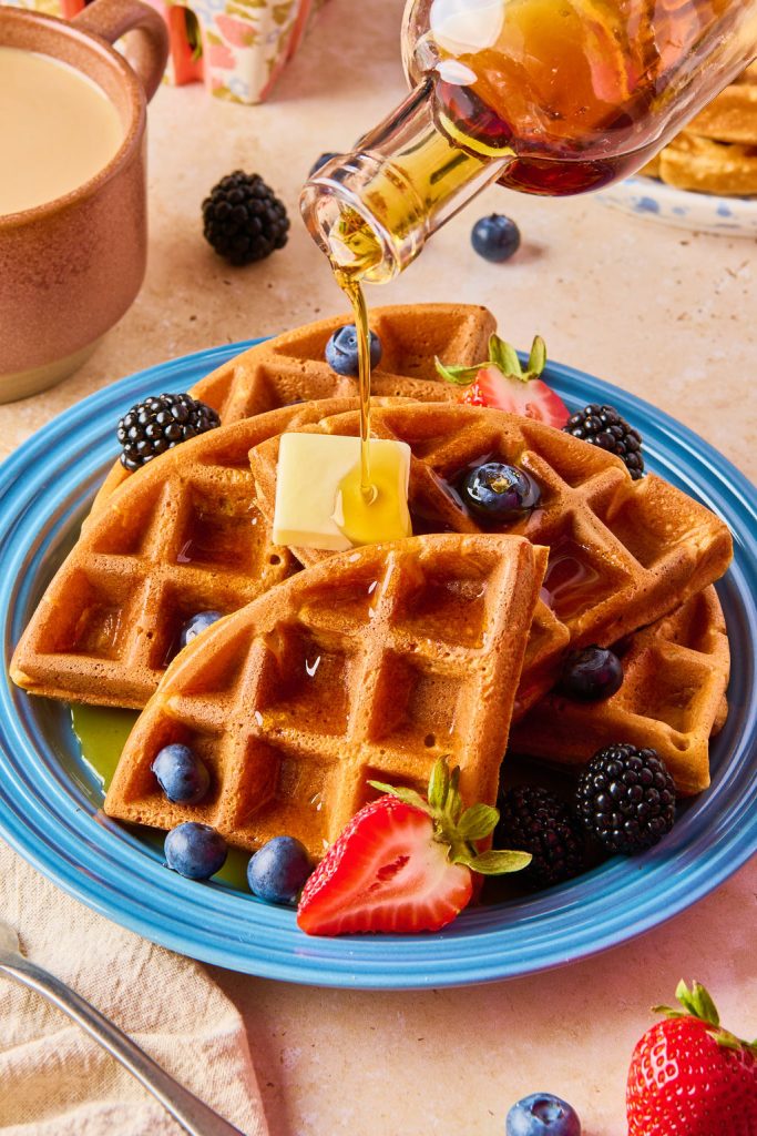 waffles stack on top of one another with butter and maple syrup