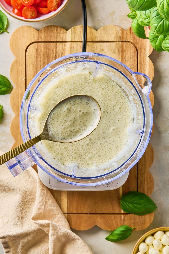 spoonful of dressing over the blender filled with pasta dressing