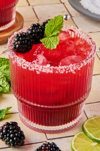 blackberry margarita in a glass topped with blackberries and mint