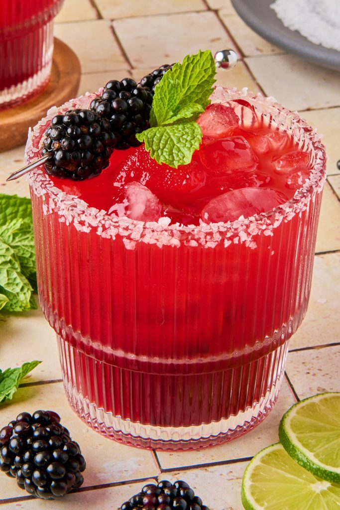 blackberry margarita in a glass topped with blackberries and mint