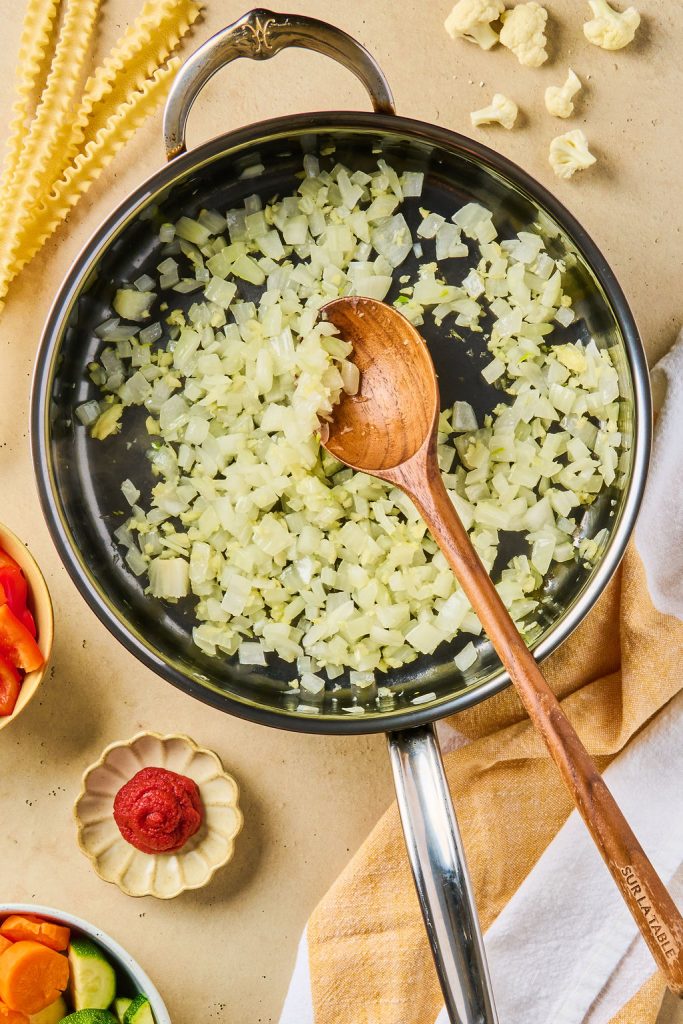 garlic mixed with onion and cooked in a skillet with a wooden spoon