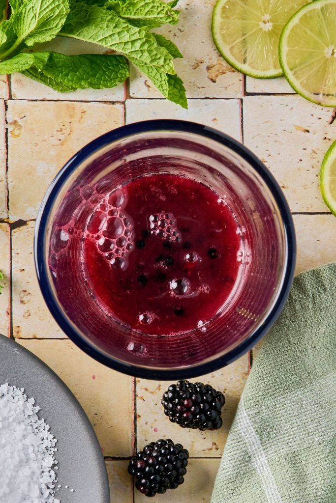 all ingredients added to muddled blackberries in a glass