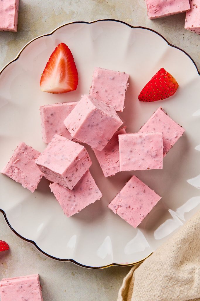 greek yogurt cut into squares and piled onto a plate with some cut up strawberries