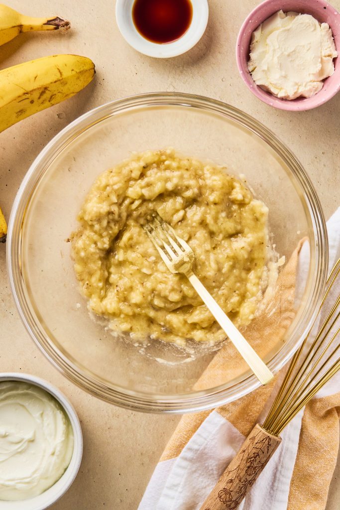 bananas being mashed in a glass bowl with a fork
