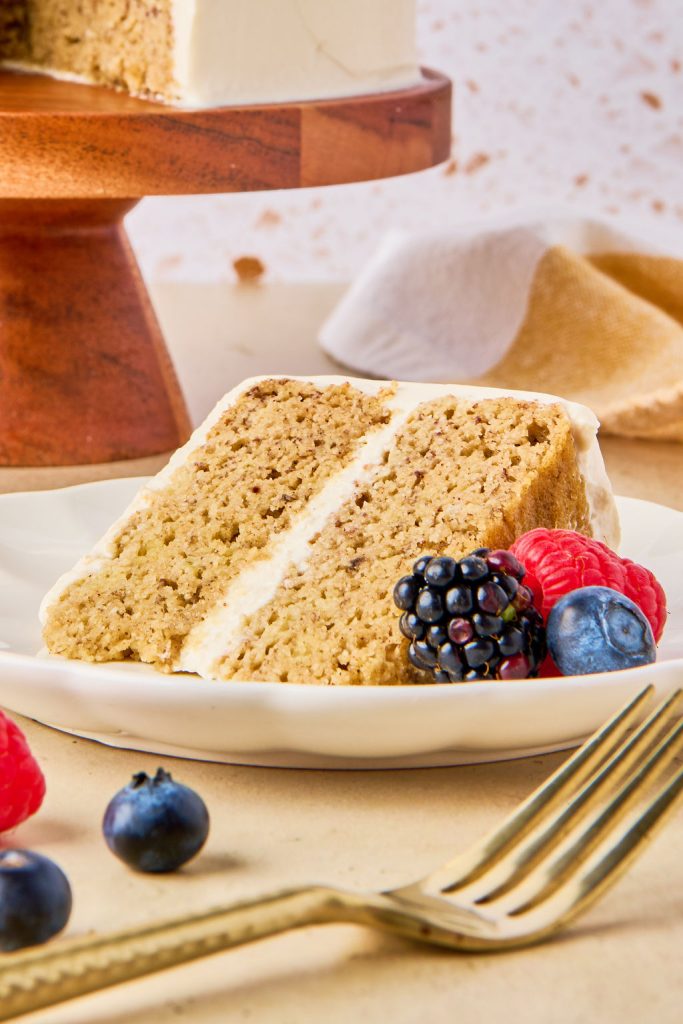 a piece of cake on a plate with fresh berries and a gold fork