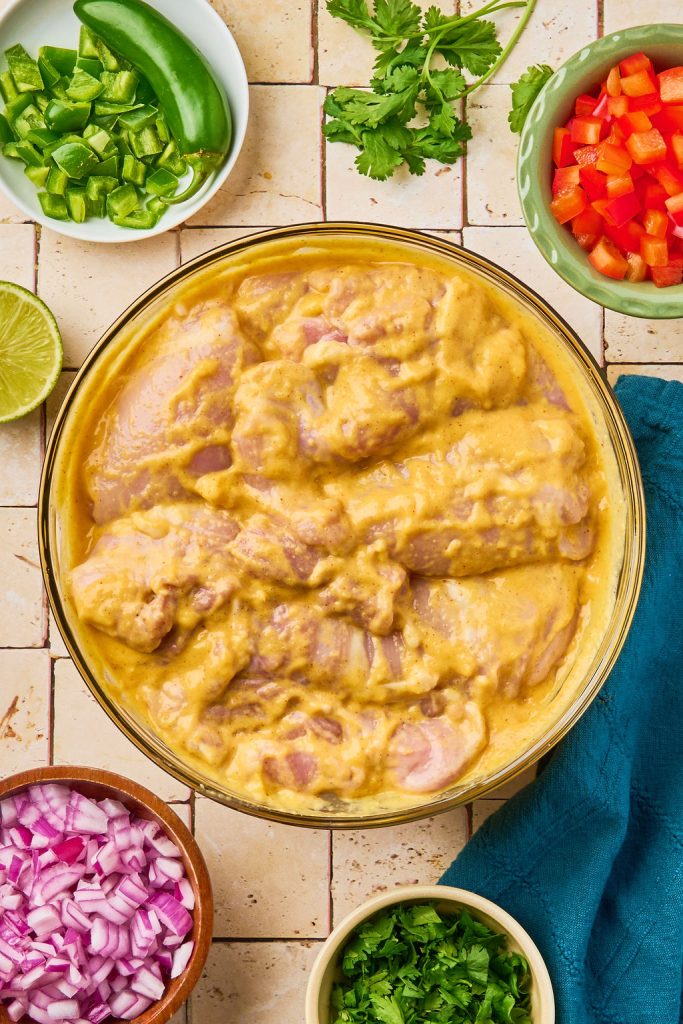 mango chicken covered in marinade in a glass bowl