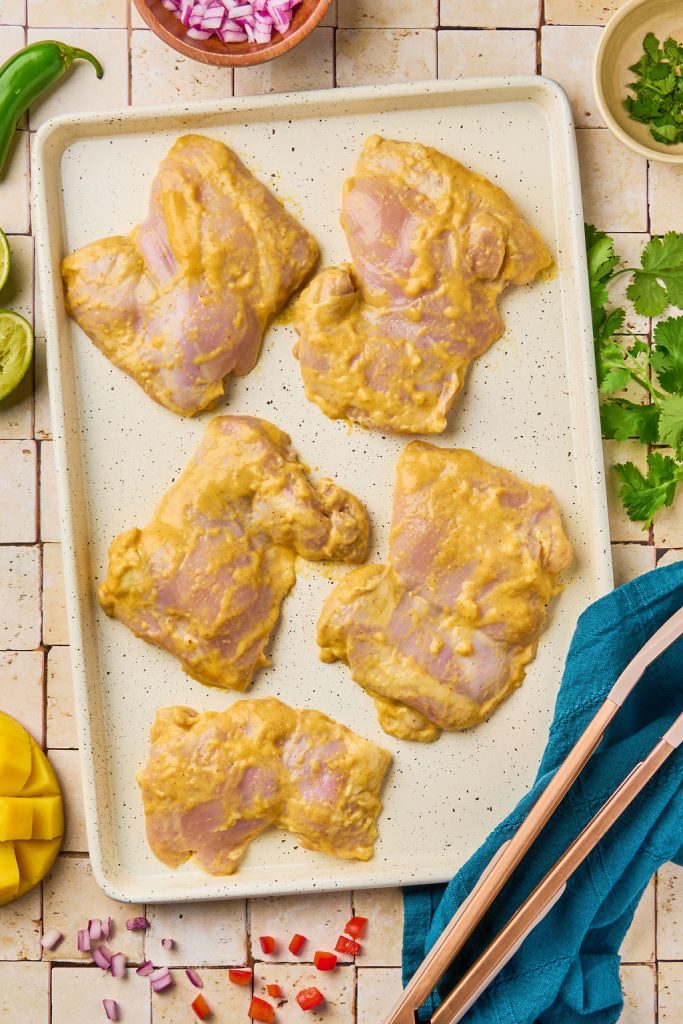 marinated mango chicken on a baking sheet