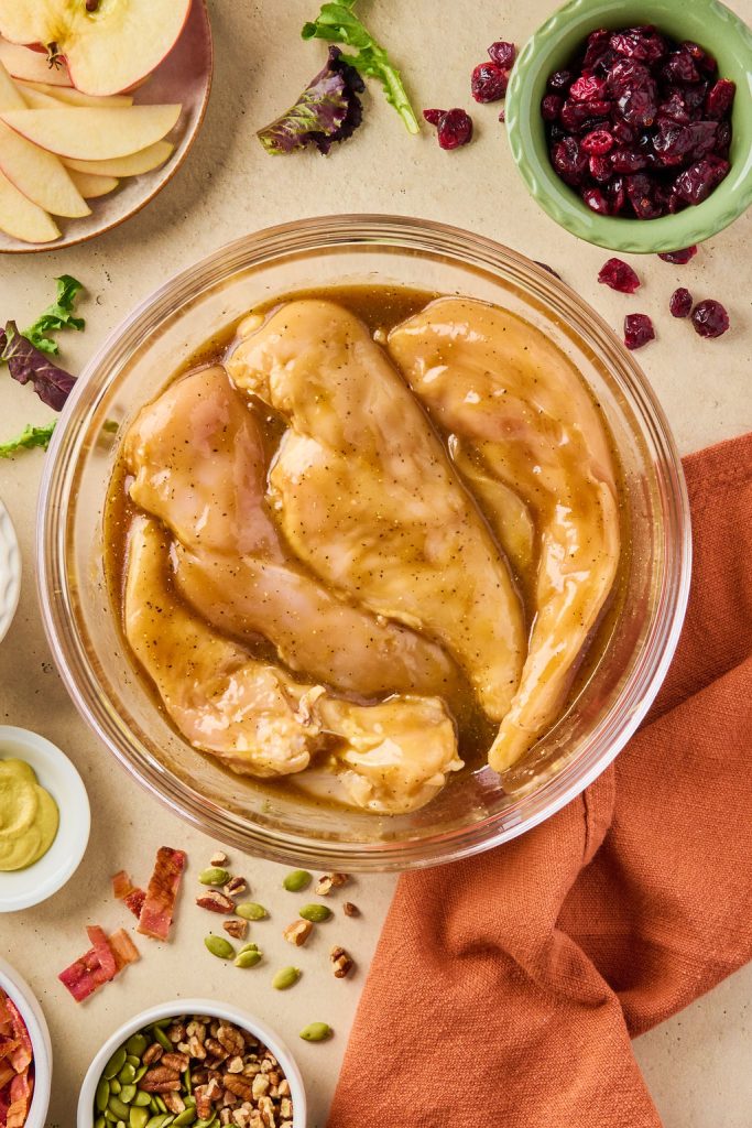 chicken breasts marinating in a glass bowl