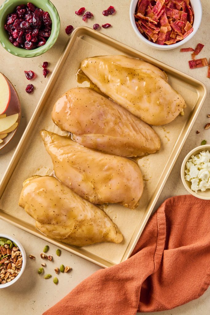 marinated chicken breasts on a baking sheet