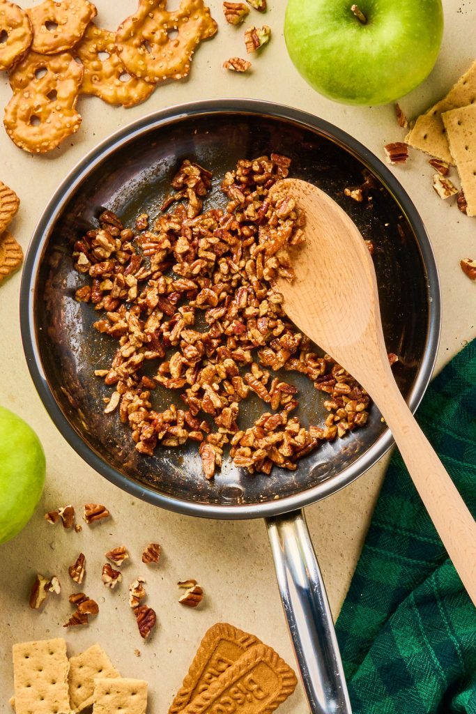 pecans coated with maple syrup and cinnamon in a skillet