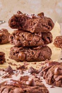 brownie batter tahini geek yogurt cookies stacked 4 high with a couple bites taken out of the cookies