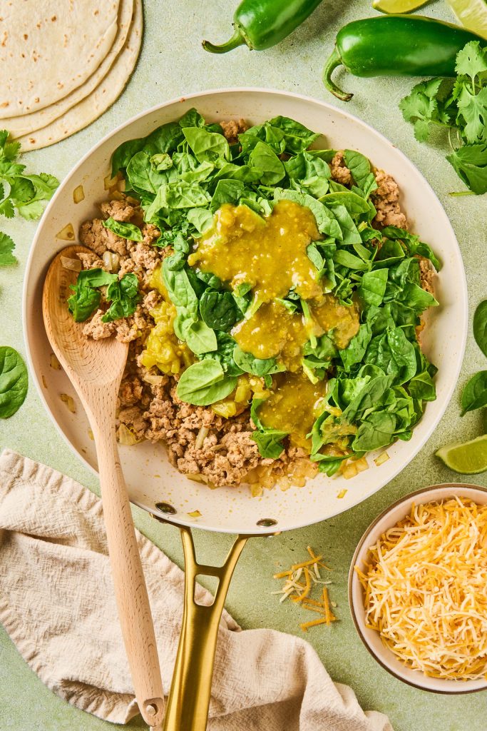 enchilada sauce and spinach added to the ground turkey in the skillet