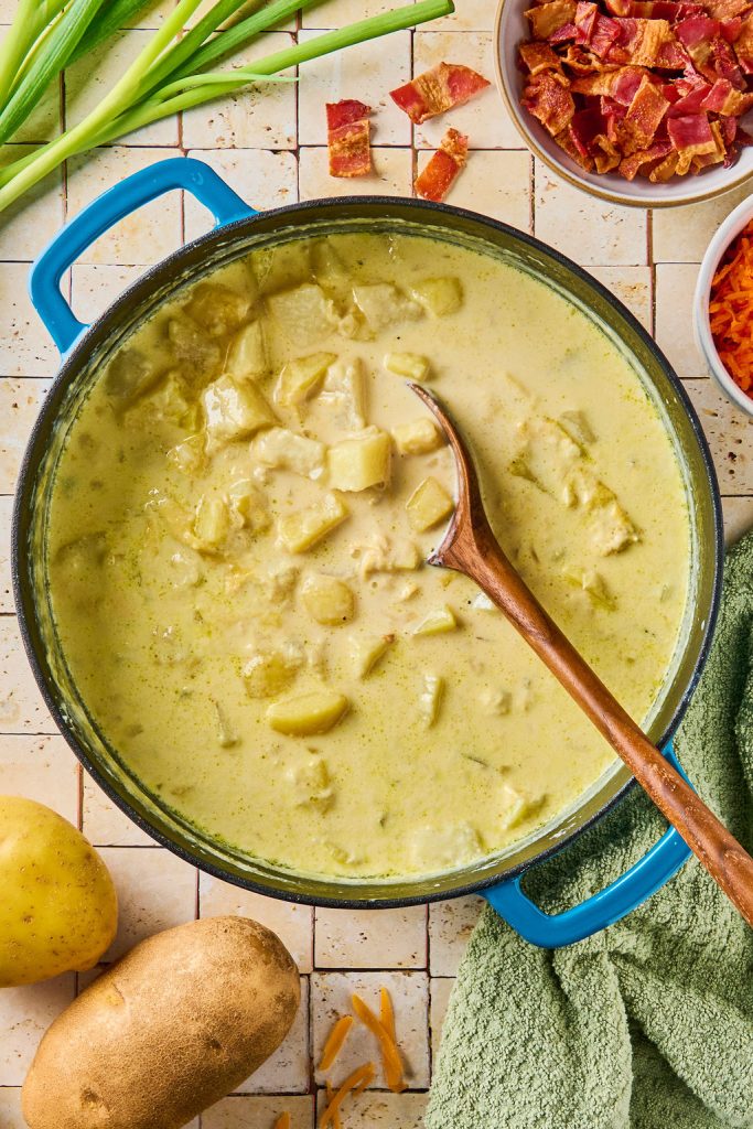 potatoes cooked in a pot until tender and being scooped with a wood spoon