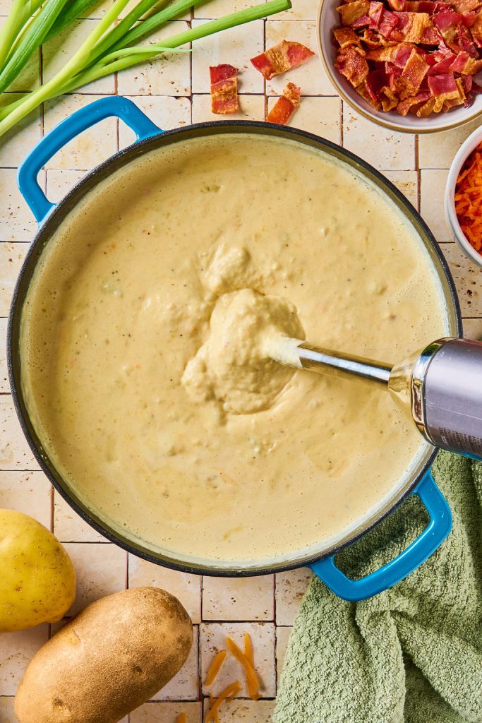 immersion blender blending the potatoes in the pot
