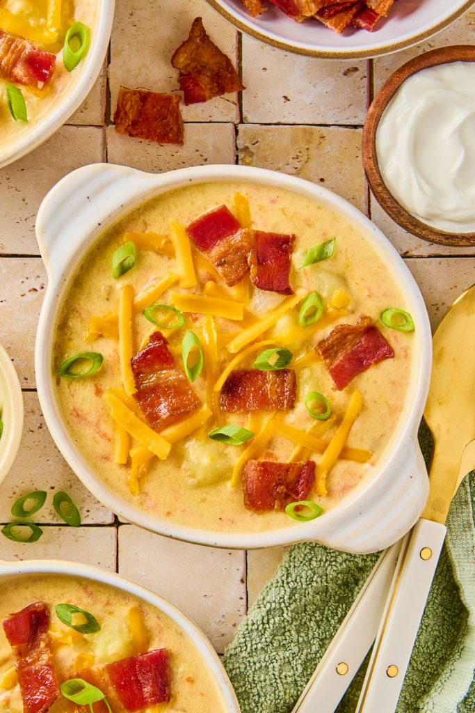 potato soup in a bowl topped with shredded cheese, green onions and bacon pieces