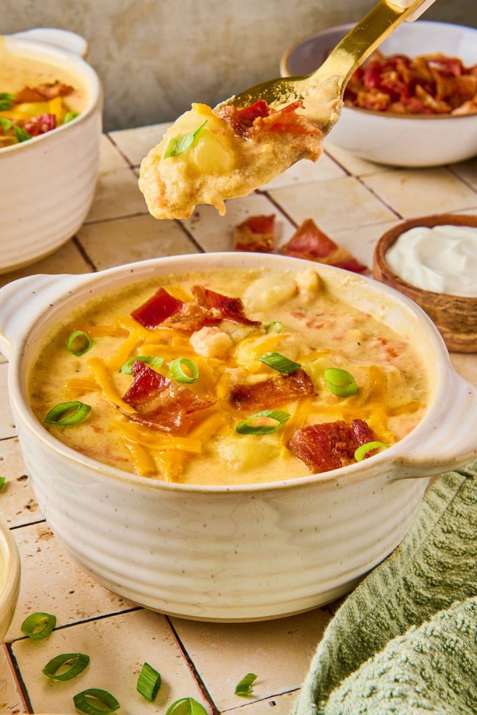 creamy potato soup in a white bowl with a spoonful being taken out
