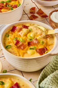 creamy easy potato soup in a bowl topped with shredded cheese, green onions and bacon
